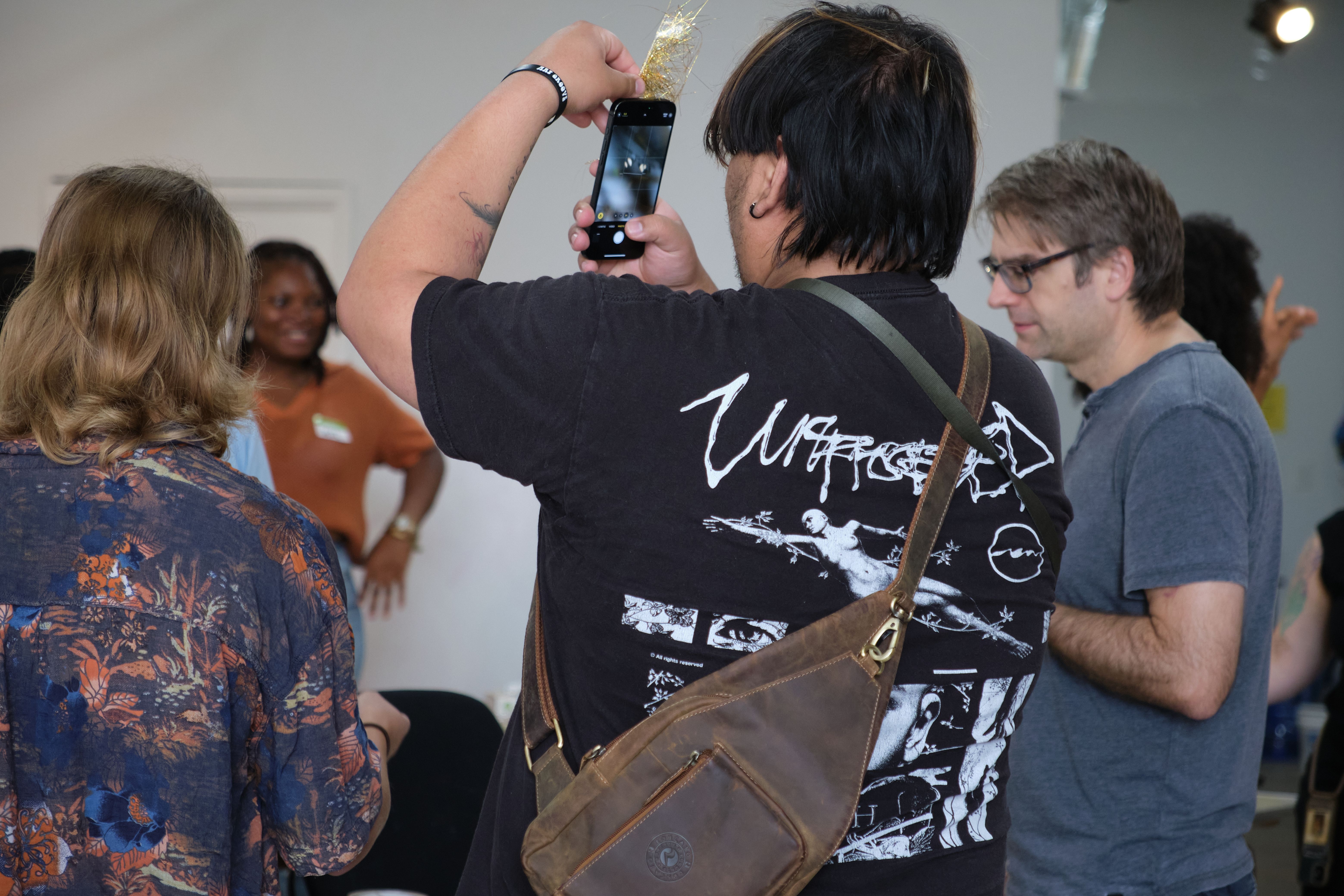 a man is taking a picture of a group of people with a cell phone .