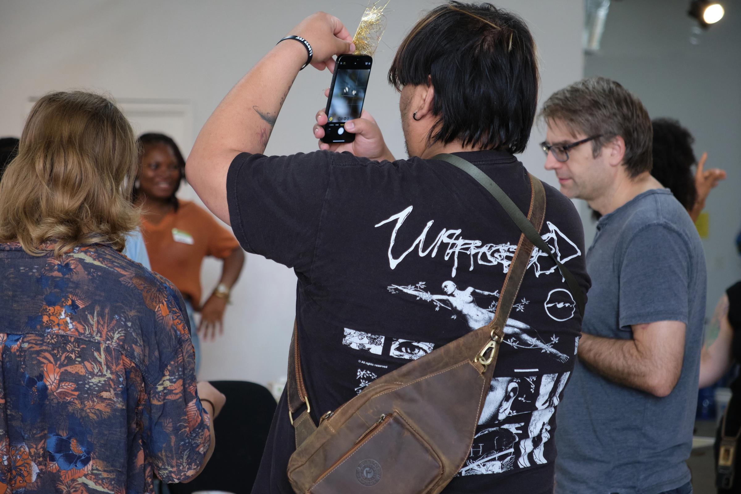 a man is taking a picture of a group of people with a cell phone .