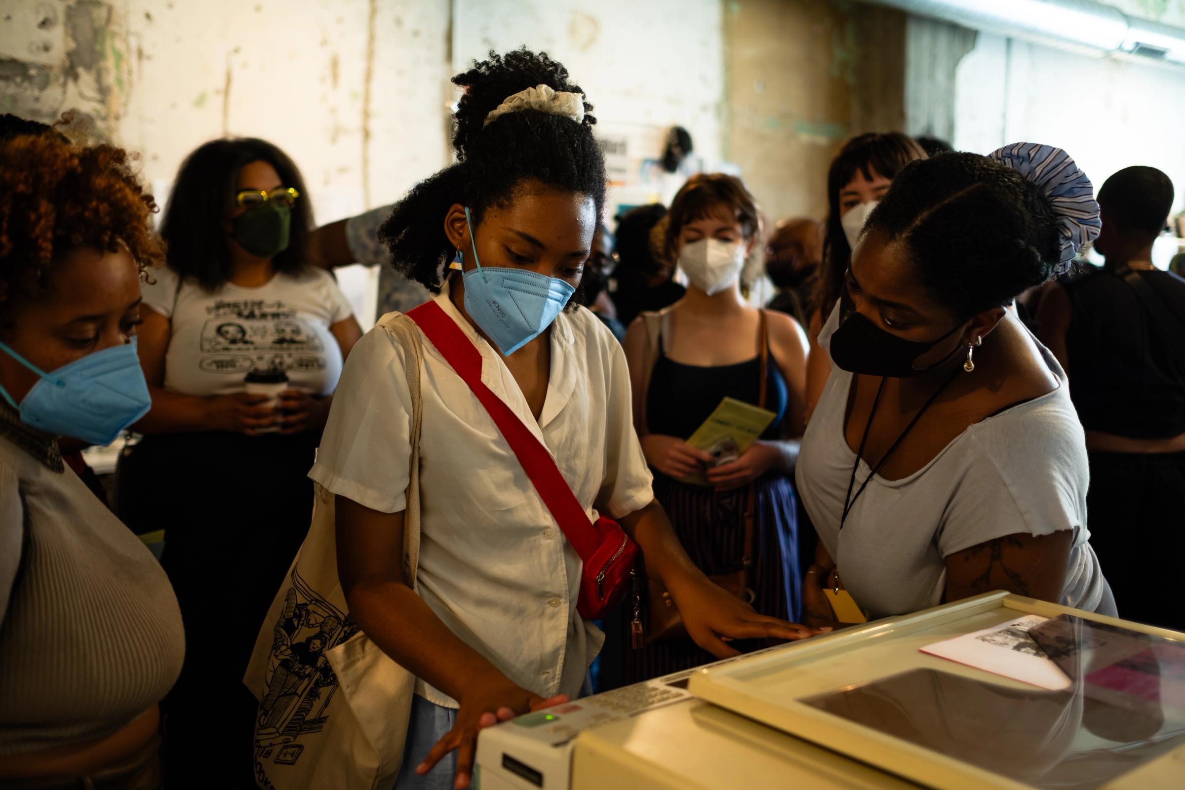 a group of women wearing face masks are looking at a machine .