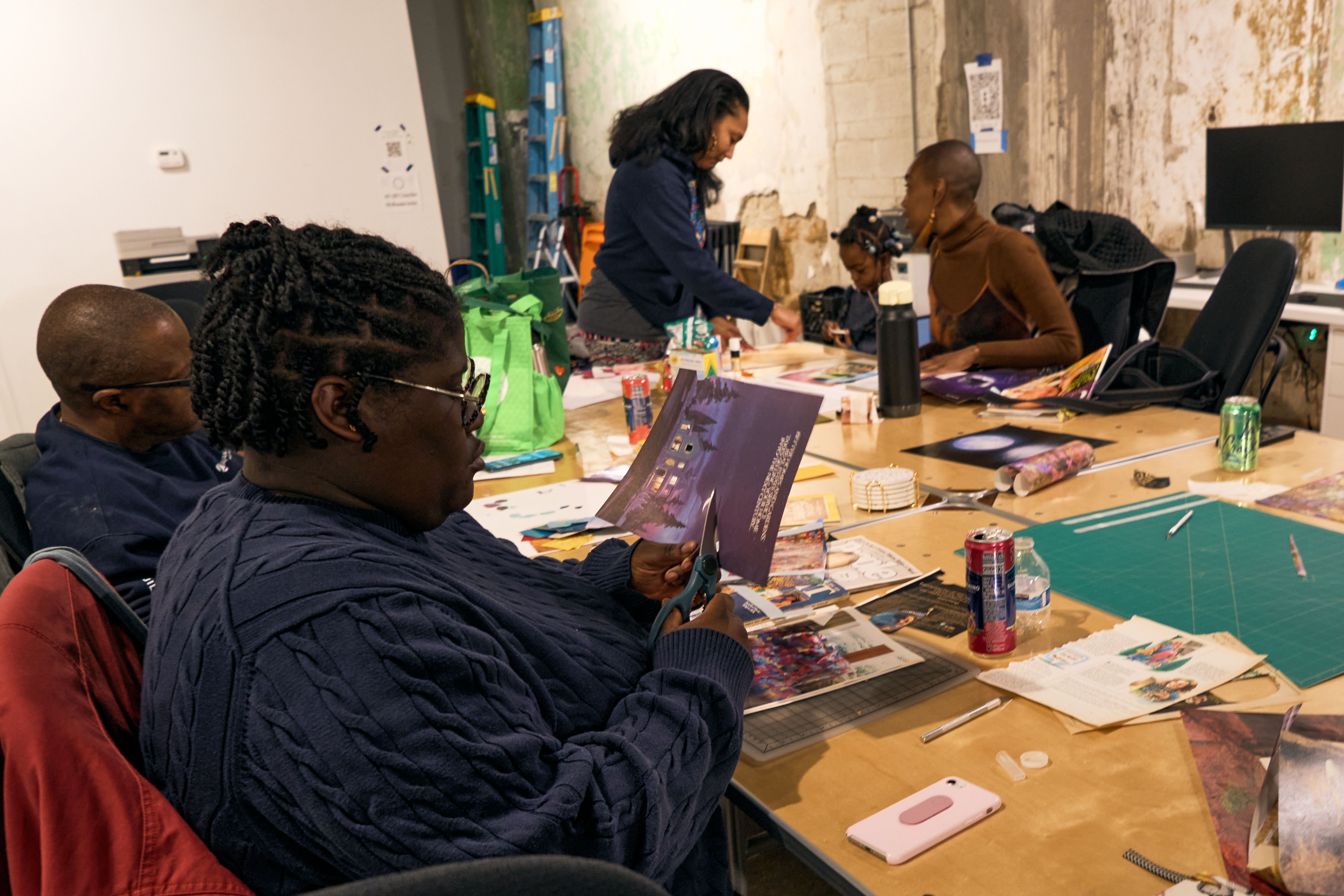 a group of people are sitting around a table making art .
