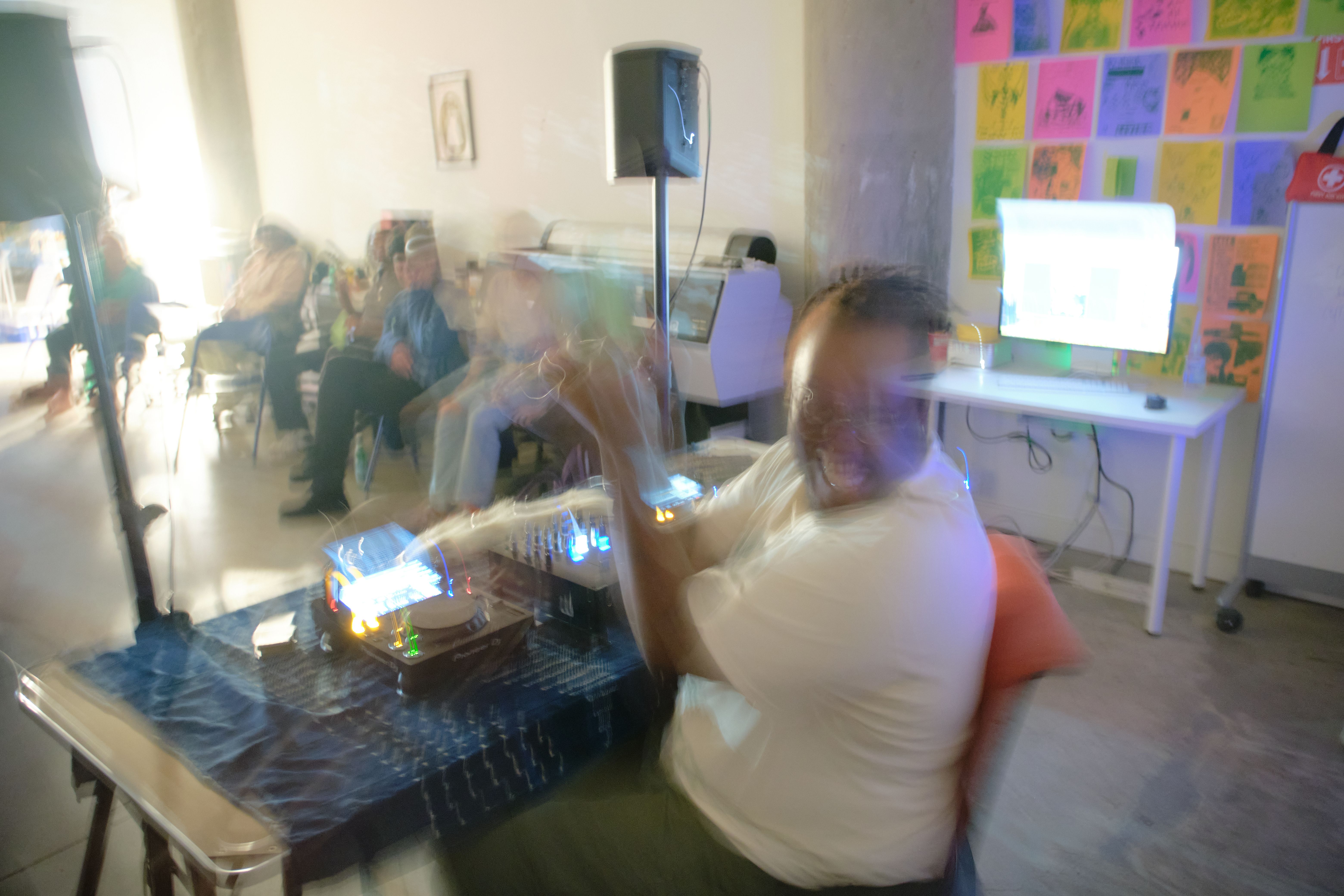 a blurry picture of a man playing using dj equipment in a room .