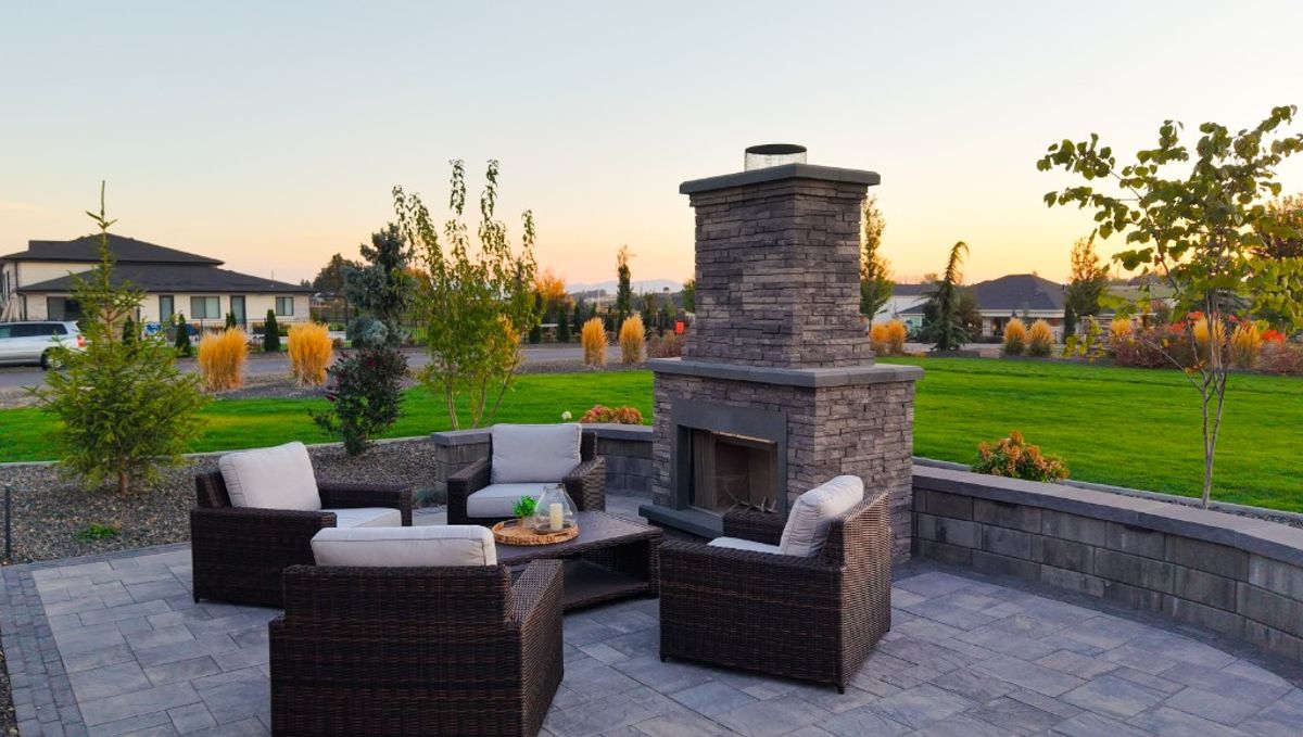 Evening view of wicker chairs facing the stone fireplace on the Caldwell paver patio