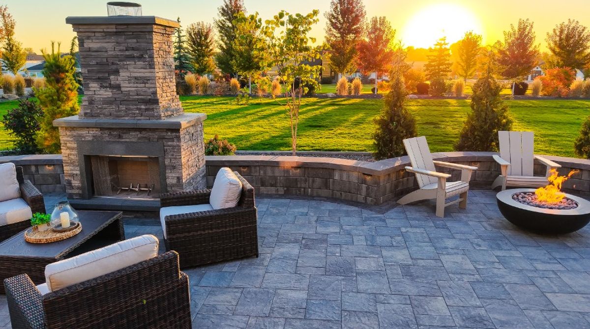 Sunset across the paver patio toward the stone fireplace and fire pit