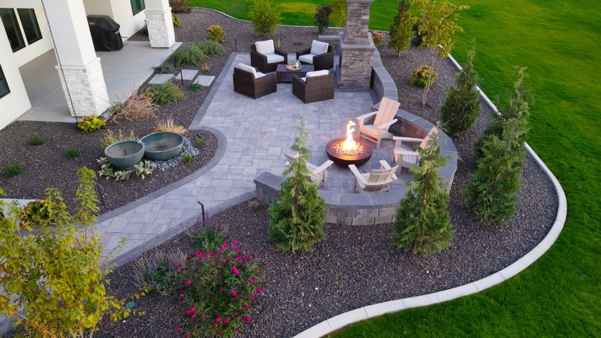Aerial of the Caldwell outdoor living room showing the fireplace seating, fire pit, fountain, and curved stone wall