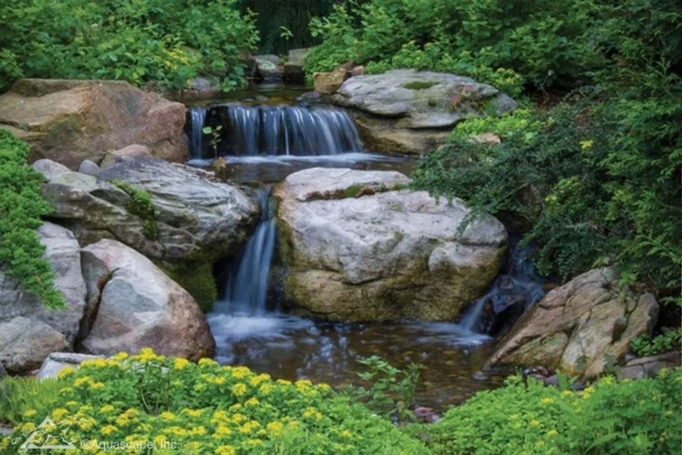 Pondless waterfall cascading over natural boulders into a stream