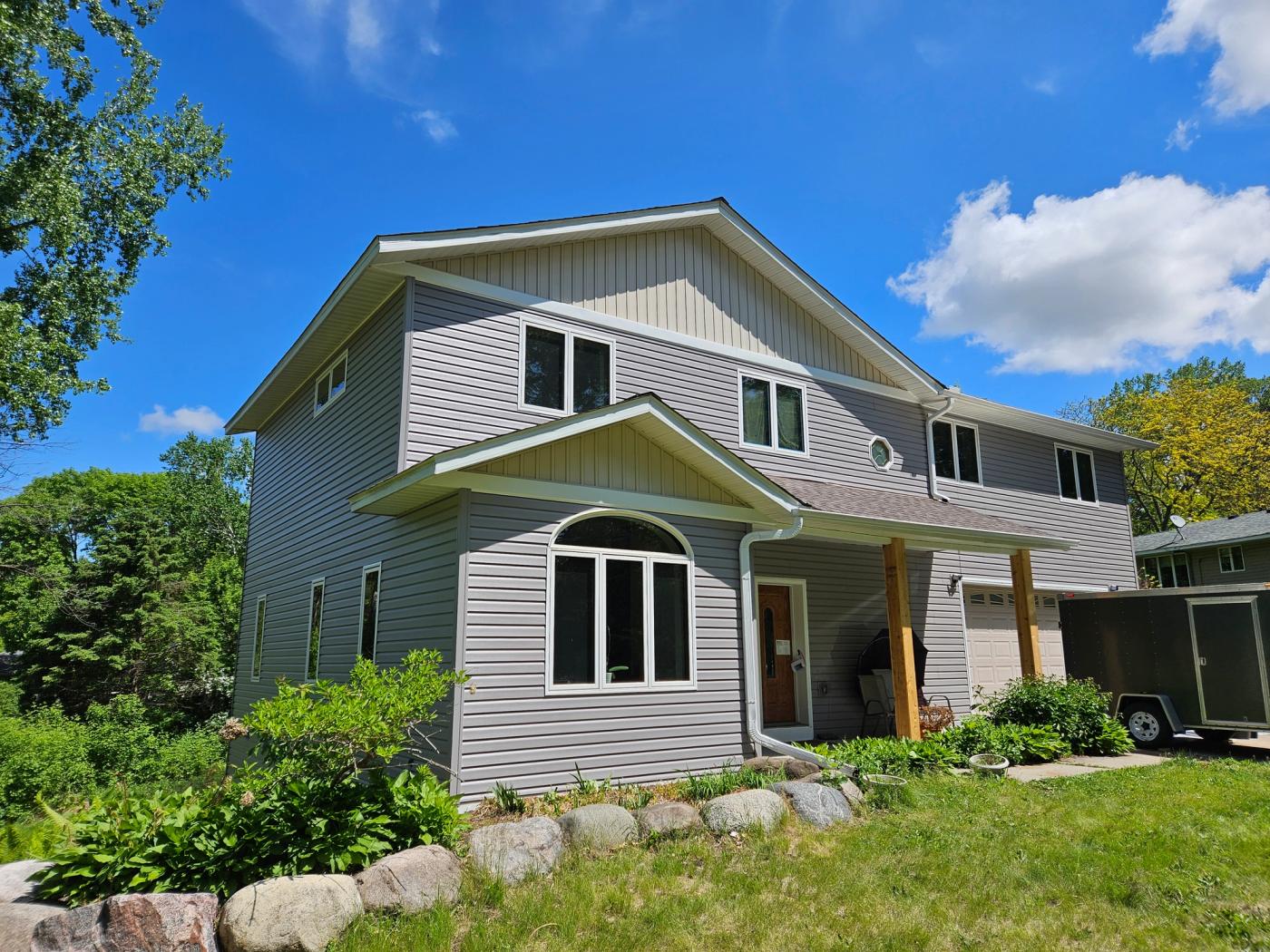 Two-story home with light gray horizontal siding, beige gable accents, and white trim.