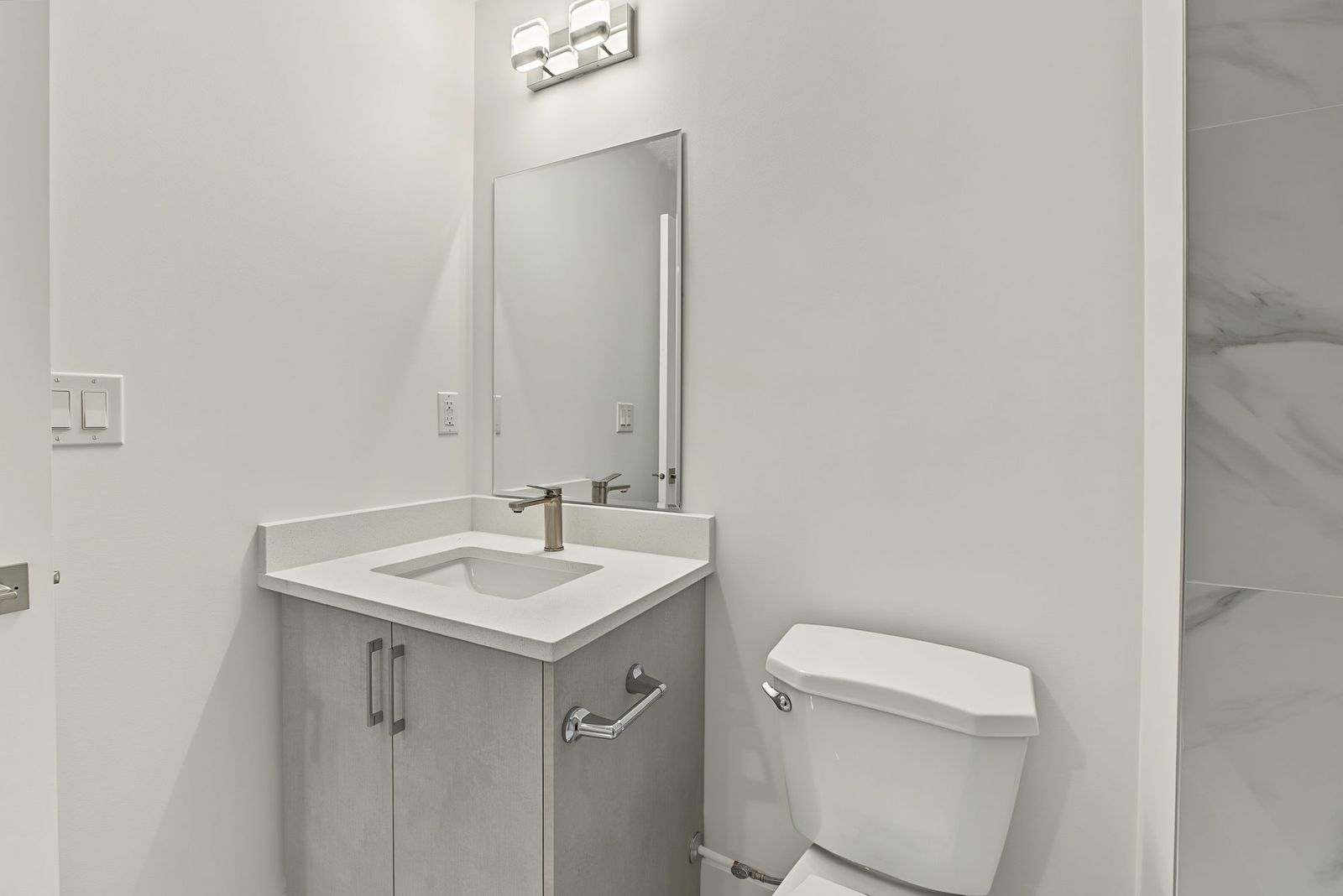 Custom vanity with quartz top, rectangular sink, chrome faucet and mirror