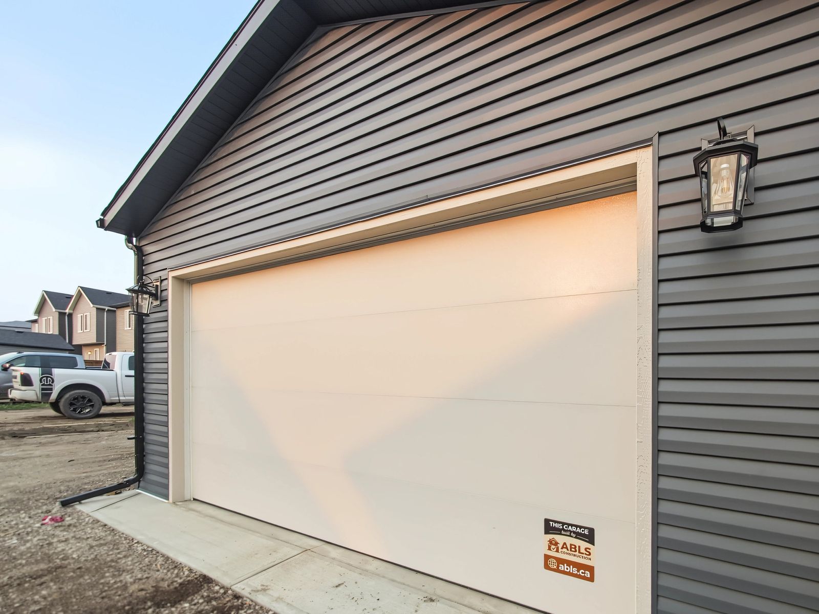 Close view up the front wall: the 16 by 8 overhead door in its trim, a black lantern and the dark fascia above