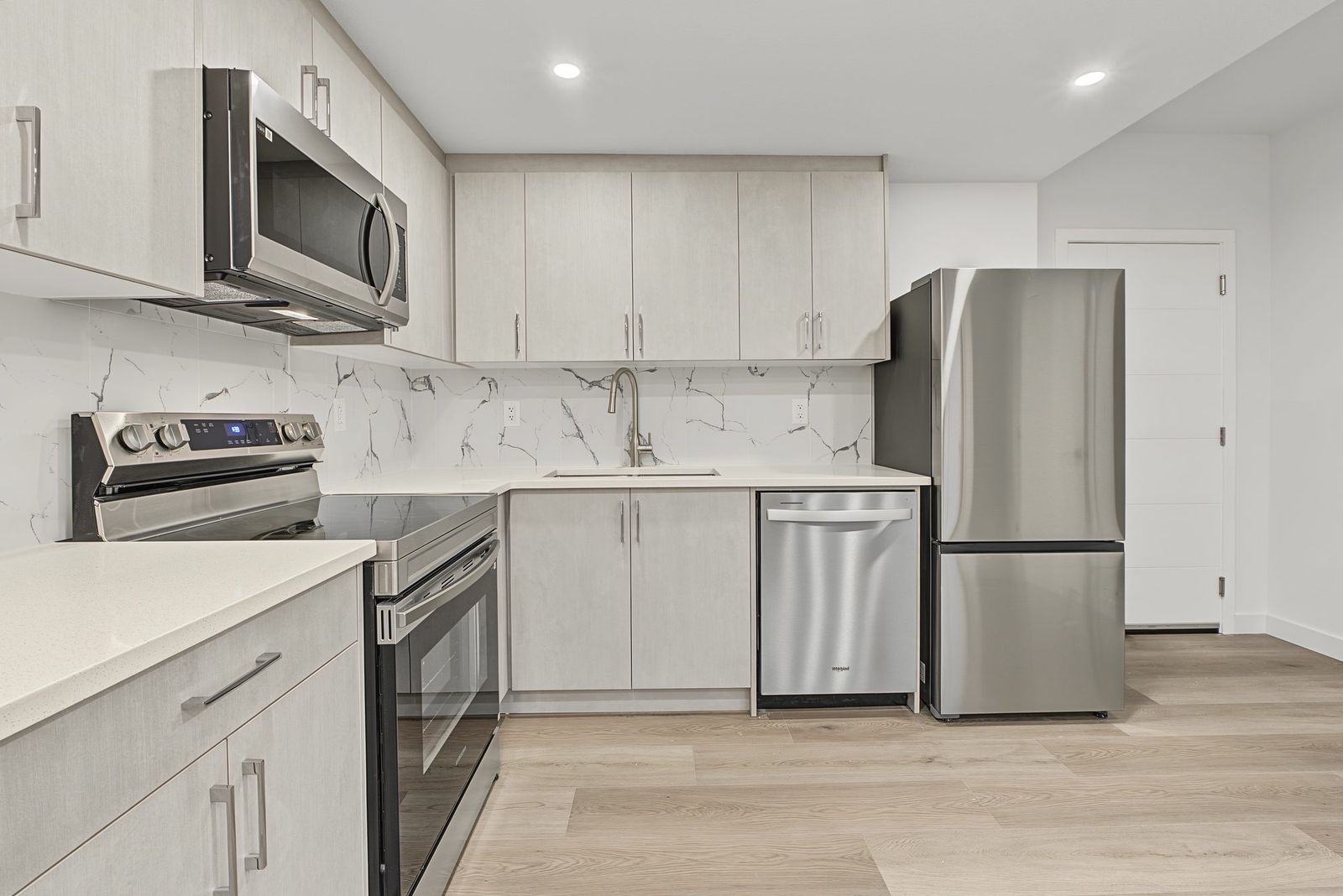 Stainless range and microwave hood against the marble-look tile backsplash