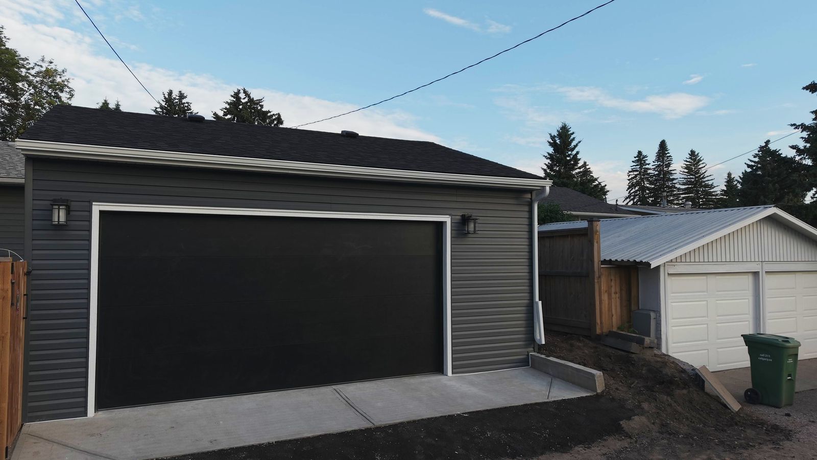 The garage from the lane with the overhead power lines passing above the ridge of the new roof