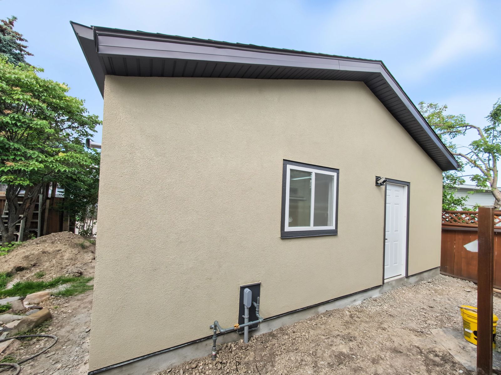 Rear corner of the garage with the sliding window, the man door and the gas line running up to the wall