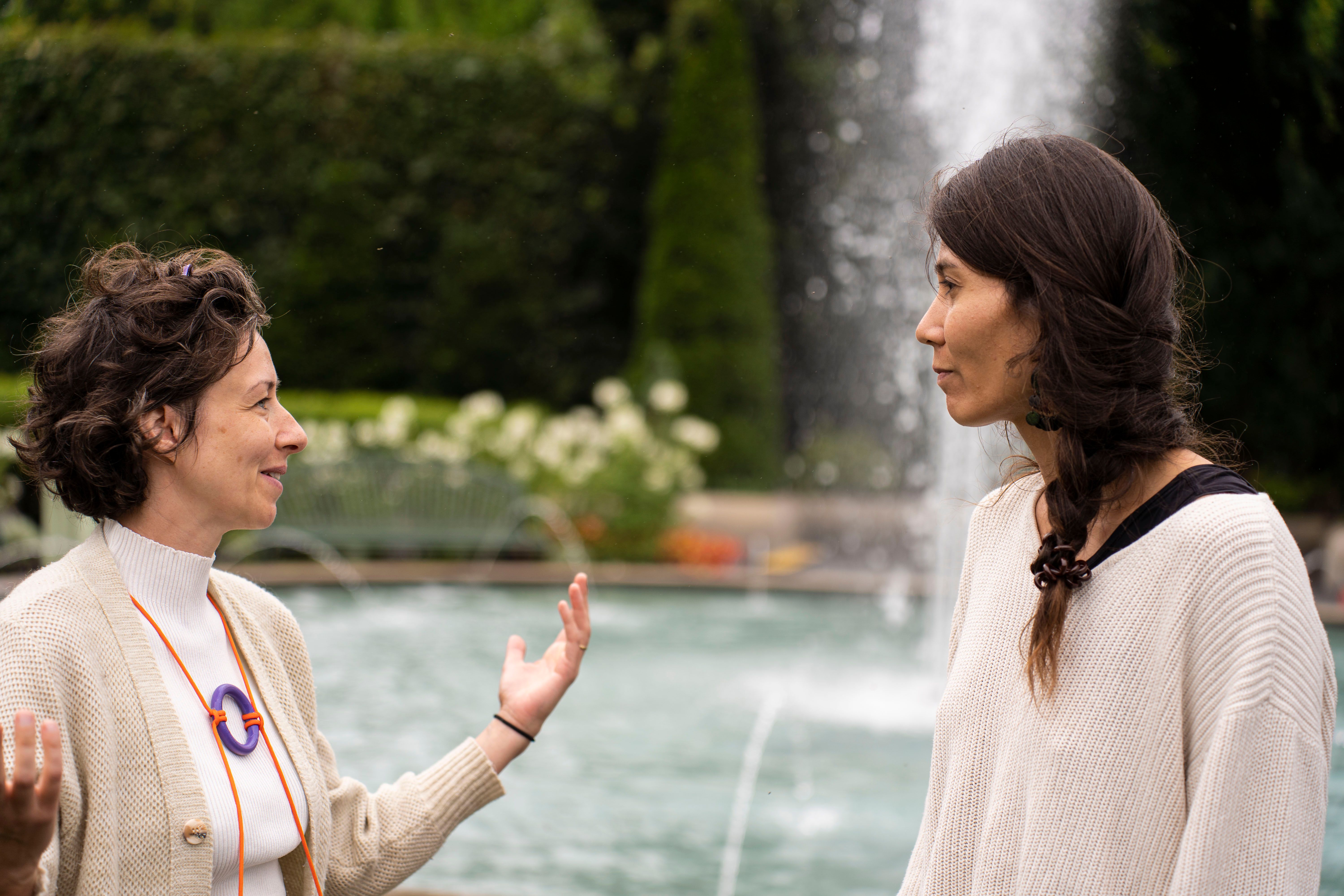 2 femmes se regardent et se parlent devant une fontaine