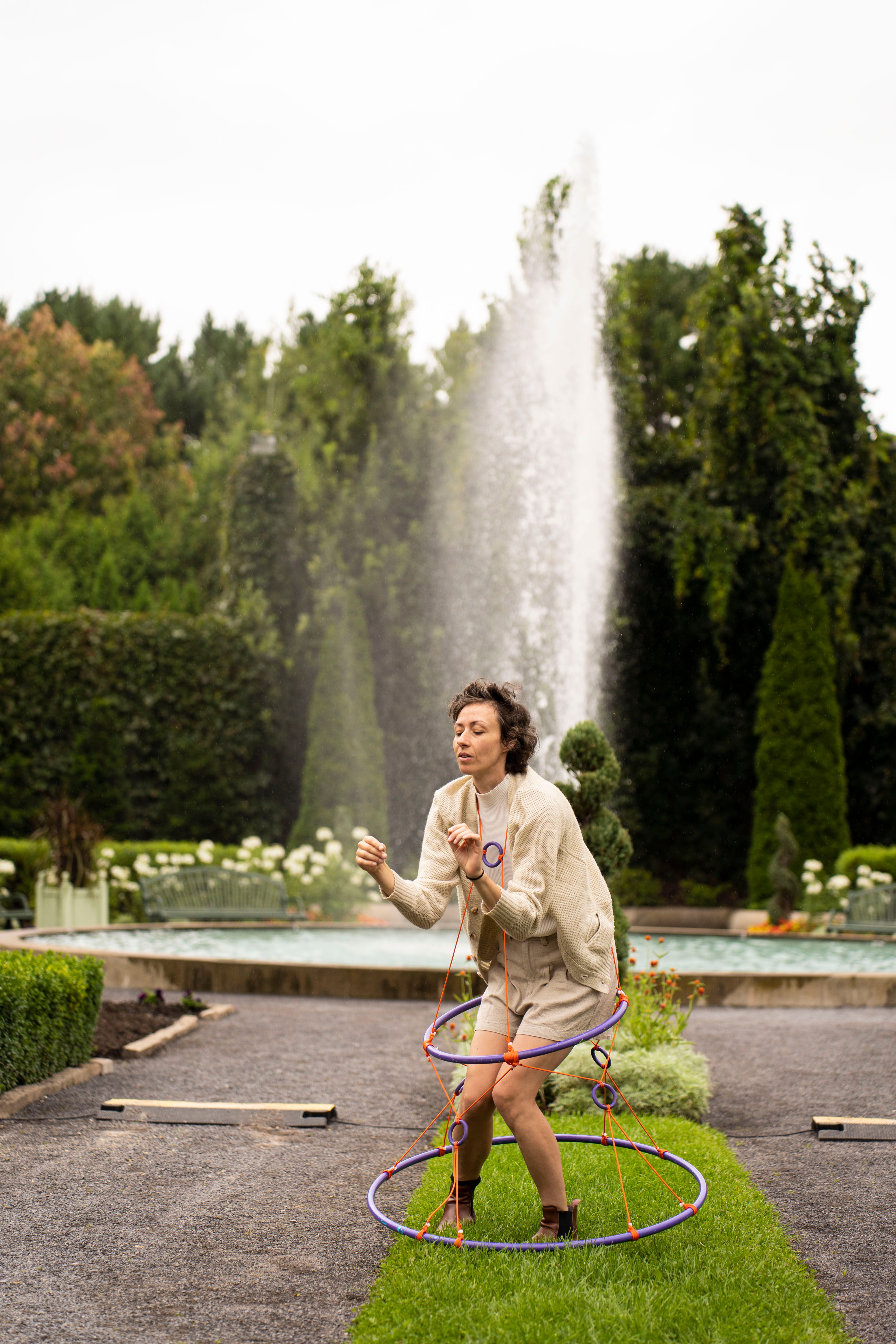 Femme devant fontaine qui danse avec des cerceaux