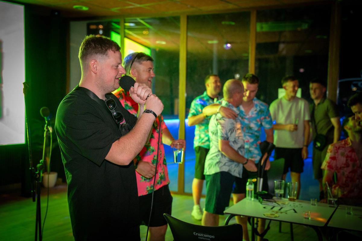A man singing karaoke at Rockstar Benidorm with his group behind him