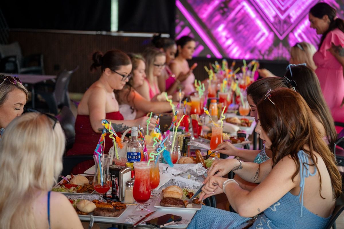 Un grupo de despedida en una mesa larga con cócteles y barbacoa en Rockstar Benidorm