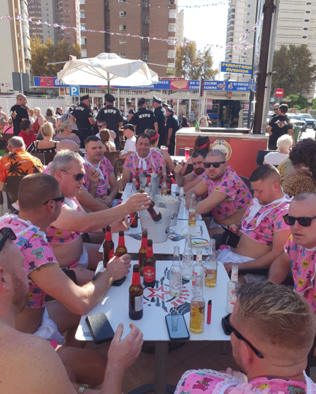 A stag group in matching shirts round a table of beers on the terrace