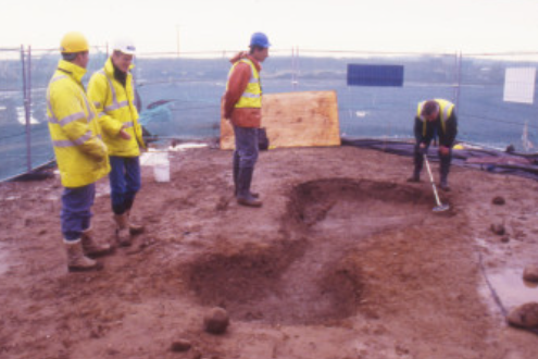 People in high-visibility clothing looking at a partially-excavated Iron Age chariot