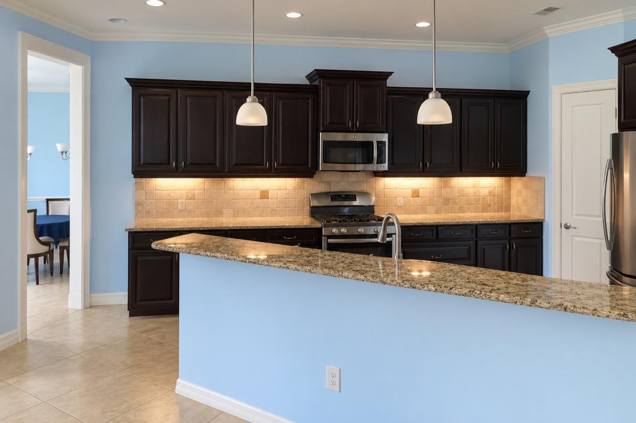 Sarasota kitchen before remodeling, with dark cabinets, blue walls and a raised peninsula.