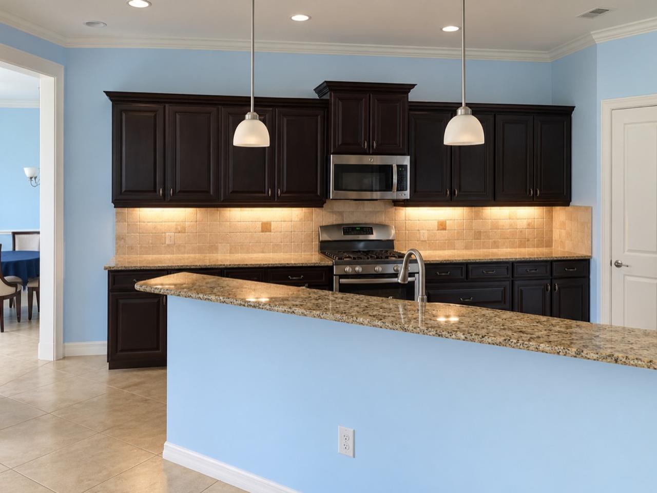 Sarasota kitchen before remodeling, with dark raised-panel cabinets, blue walls, beige tile backsplash and a raised peninsula.