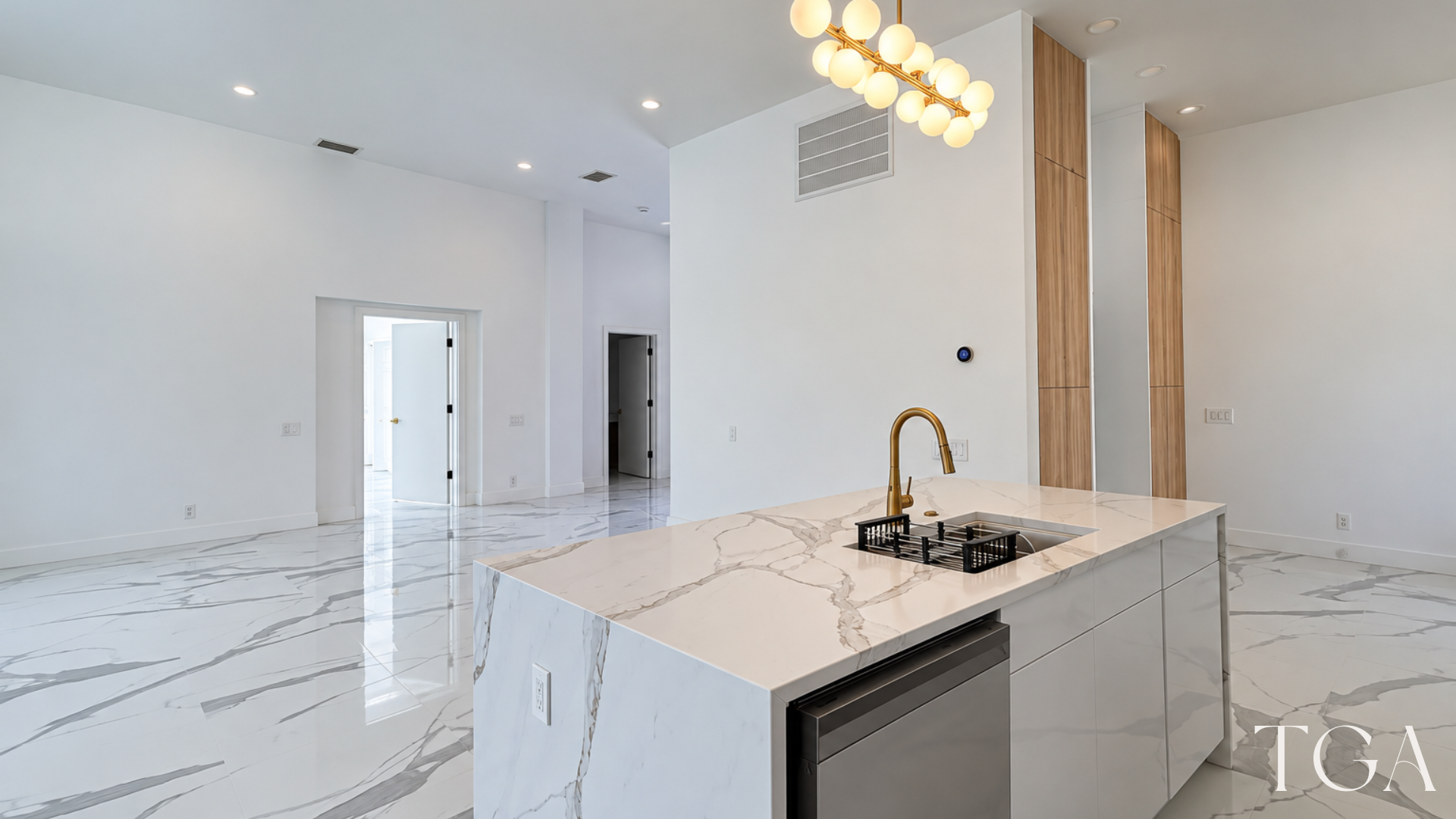 Kitchen island with a sink, gold faucet and dishwasher overlooking the open living area.