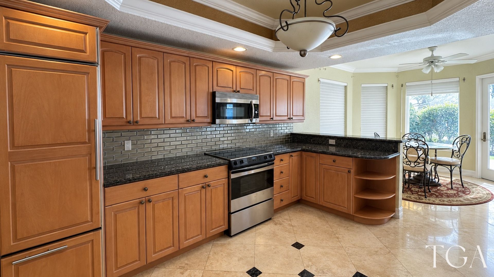 Before view of the brown kitchen cabinets and dark counters beside the dining area