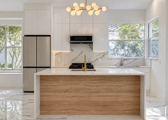 Custom white kitchen with a wood-tone waterfall island and gold globe lighting in a Sarasota whole-home remodel.