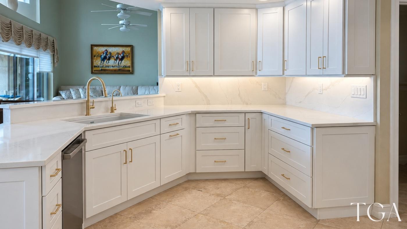 White cabinets and a gold-tone faucet beside a light backsplash illuminated by under-cabinet lighting.