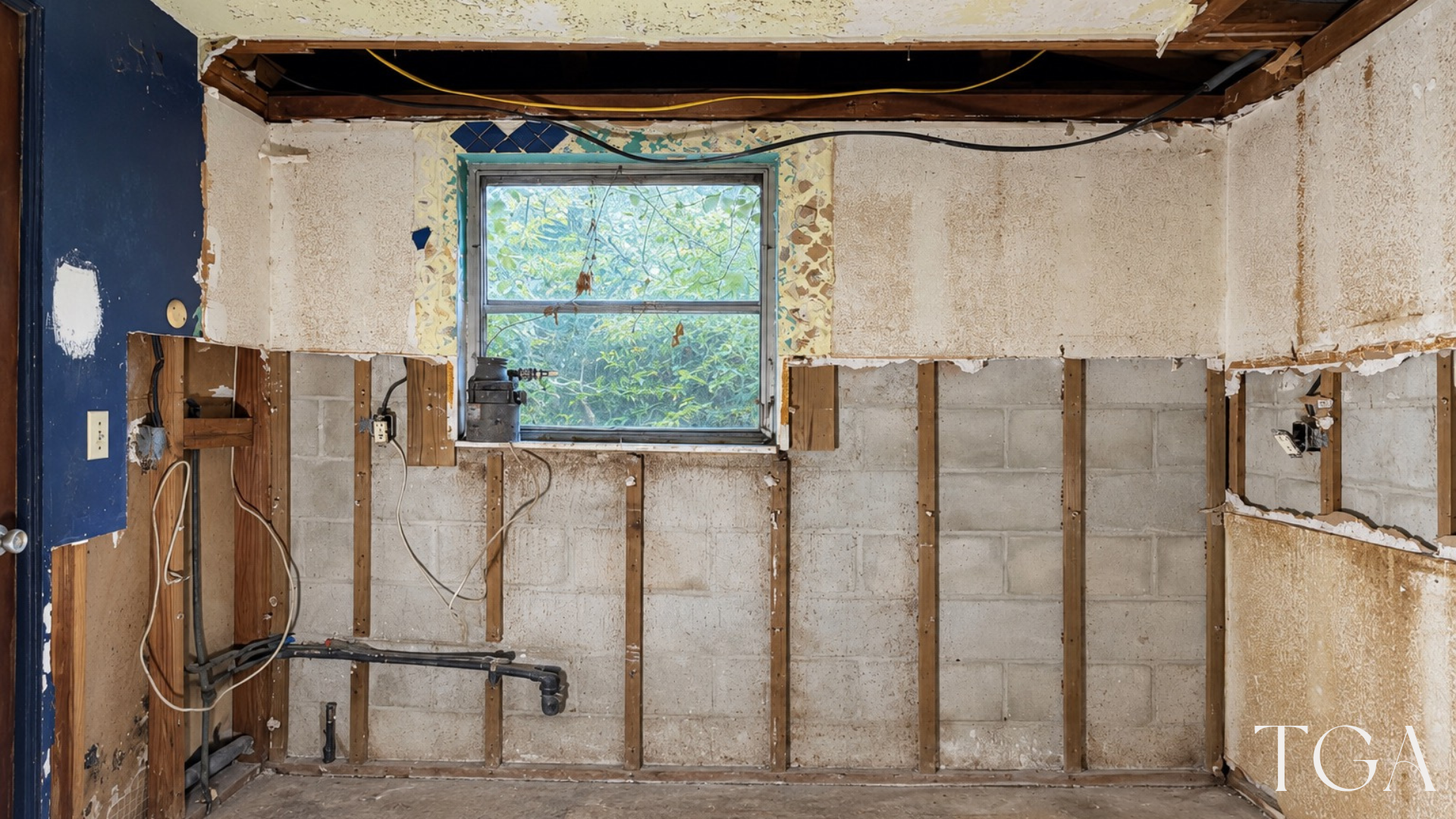 Wide view of the two-tone kitchen window wall with exposed masonry, framing and plumbing during construction