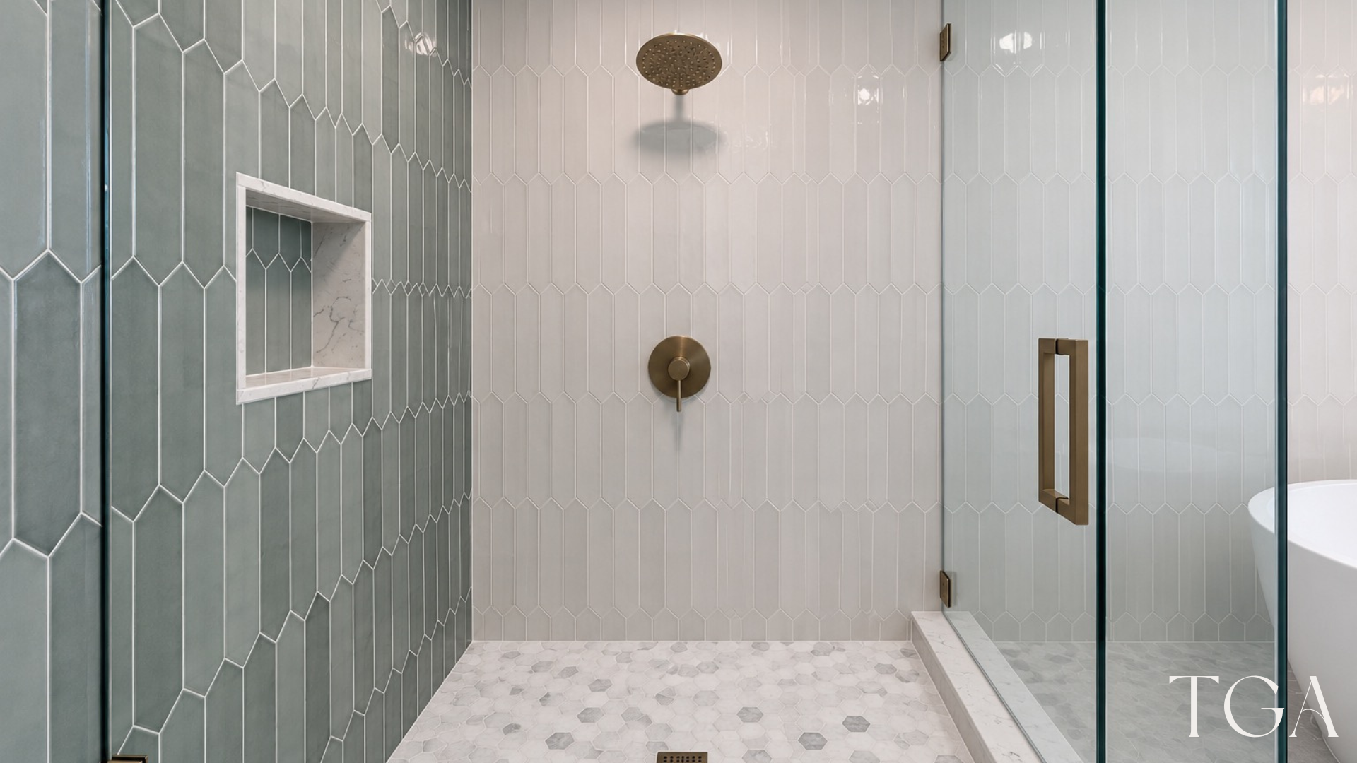 Walk-in shower with elongated blue-green accent tile, recessed niche, overhead shower fixture and mosaic floor