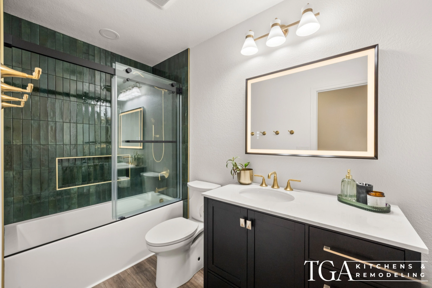 Updated tub and shower combo with dark green tile, glass sliding doors, and brass fixtures in a St. Petersburg bathroom remodel