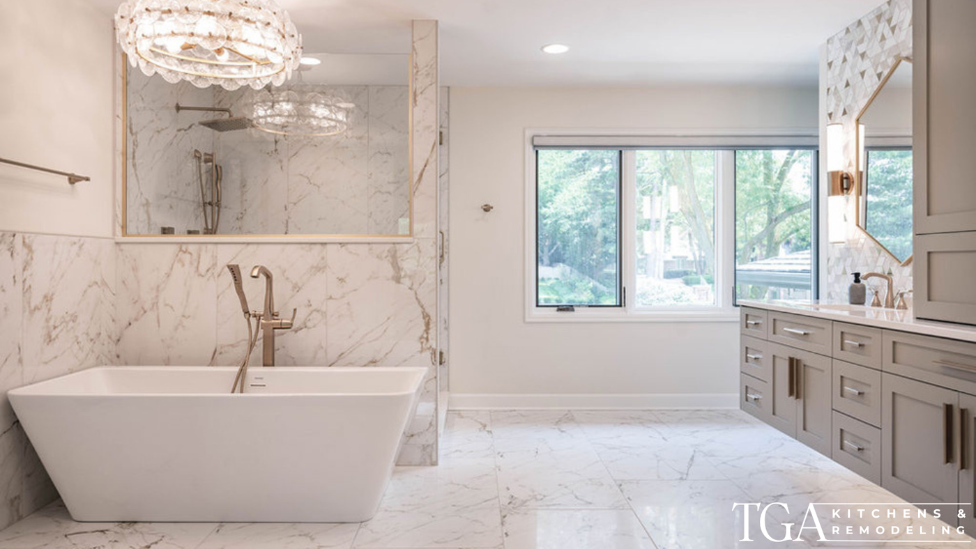 Upscale primary bathroom remodel with marble-look tile, freestanding tub, glass shower, and chandelier lighting