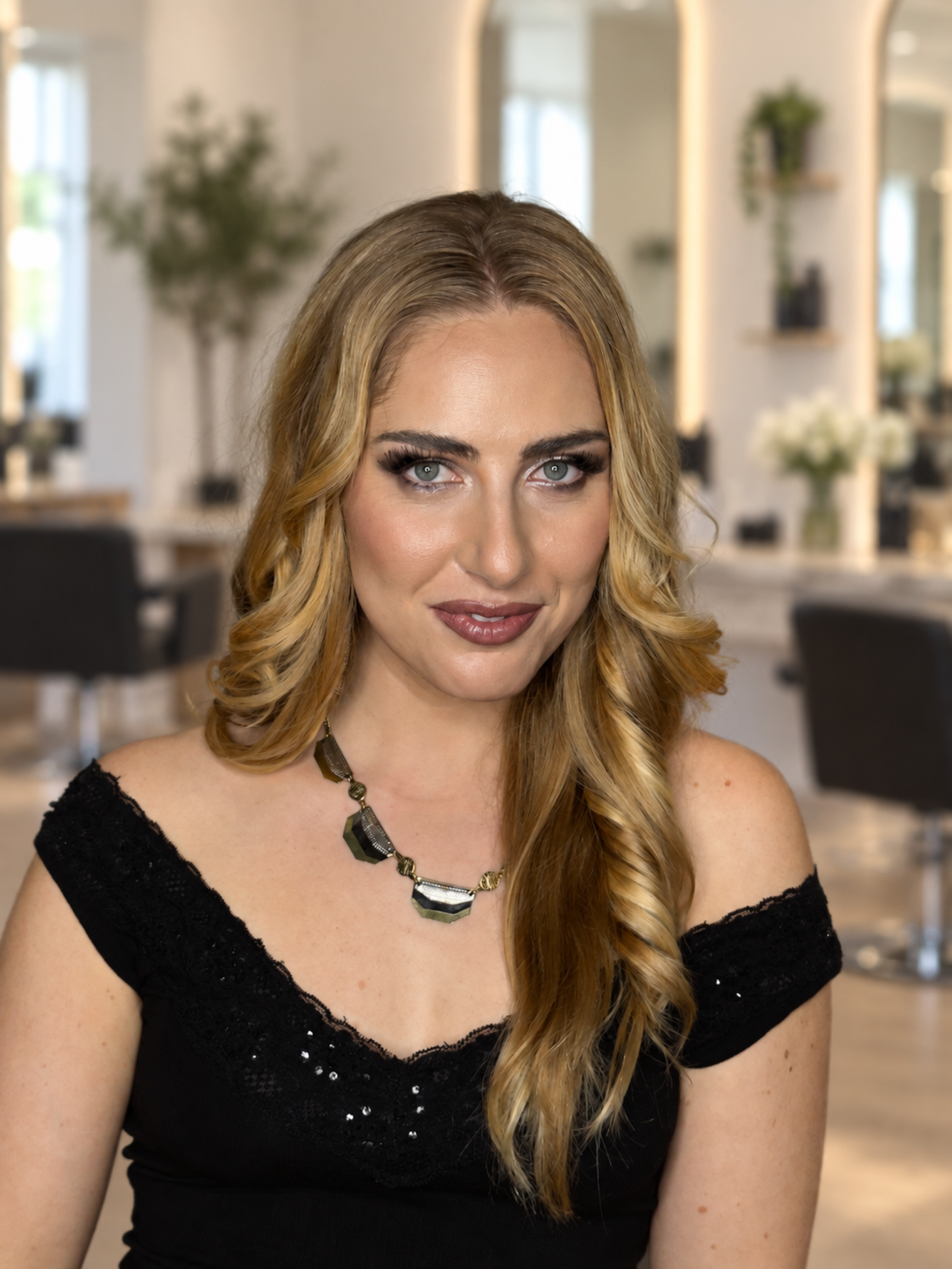 Blonde woman with polished side-swept waves and glamorous neutral makeup.