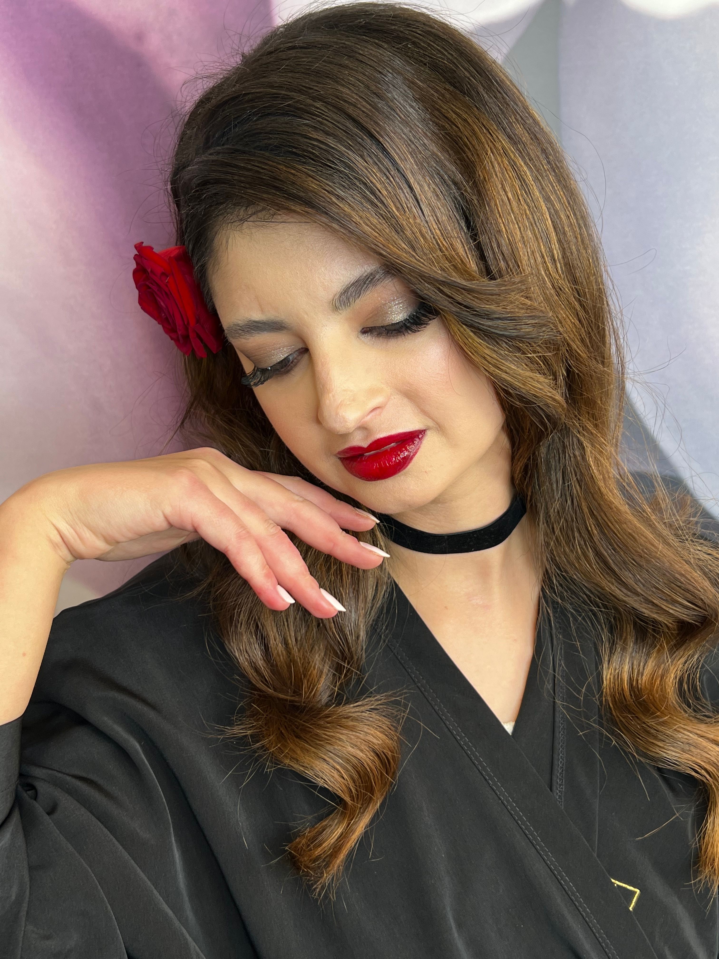 Brunette woman with side-swept waves, smoky eyes, and bold red lipstick.