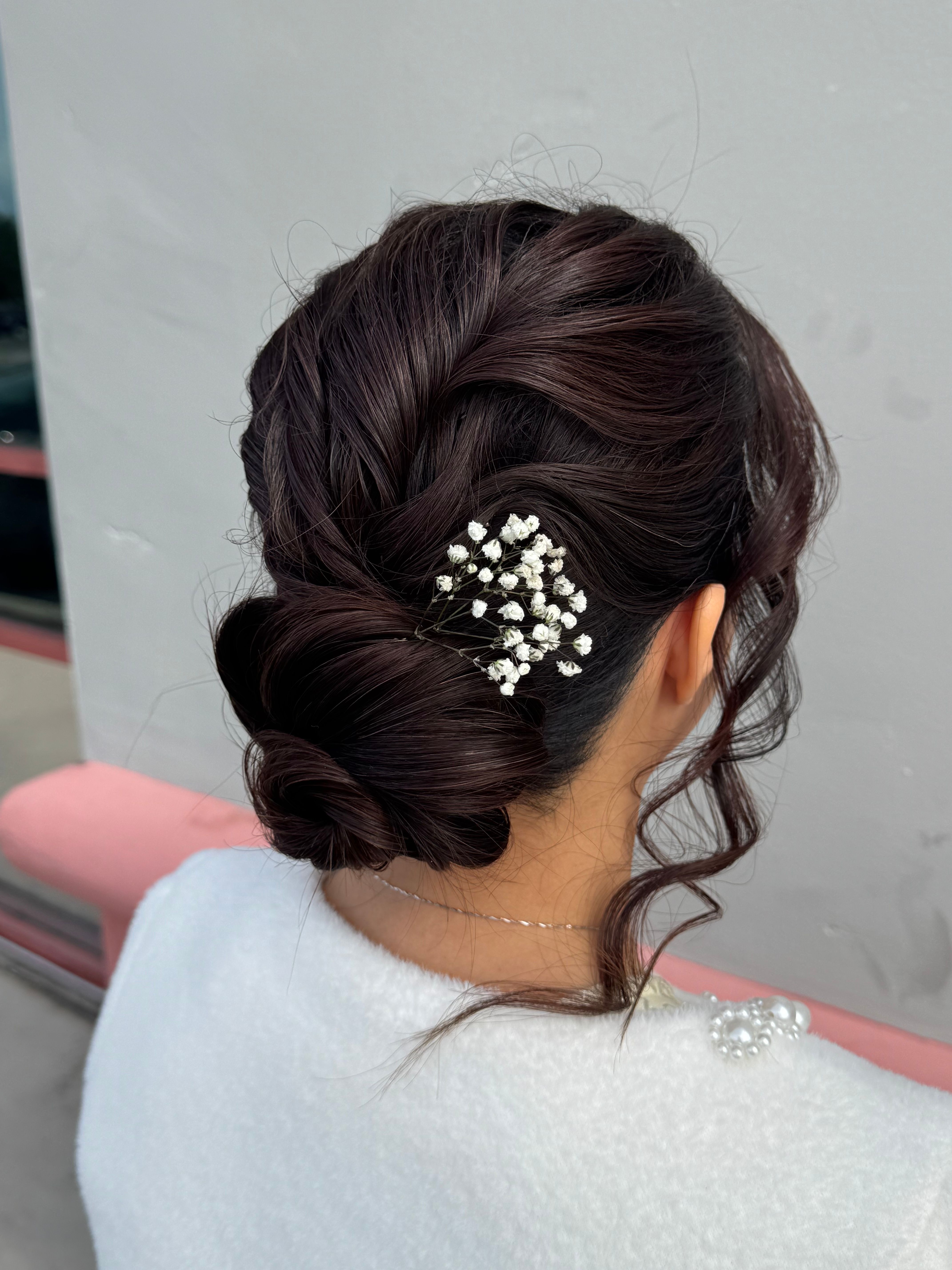 Back view of a textured low brunette updo decorated with a silver floral hairpiece.