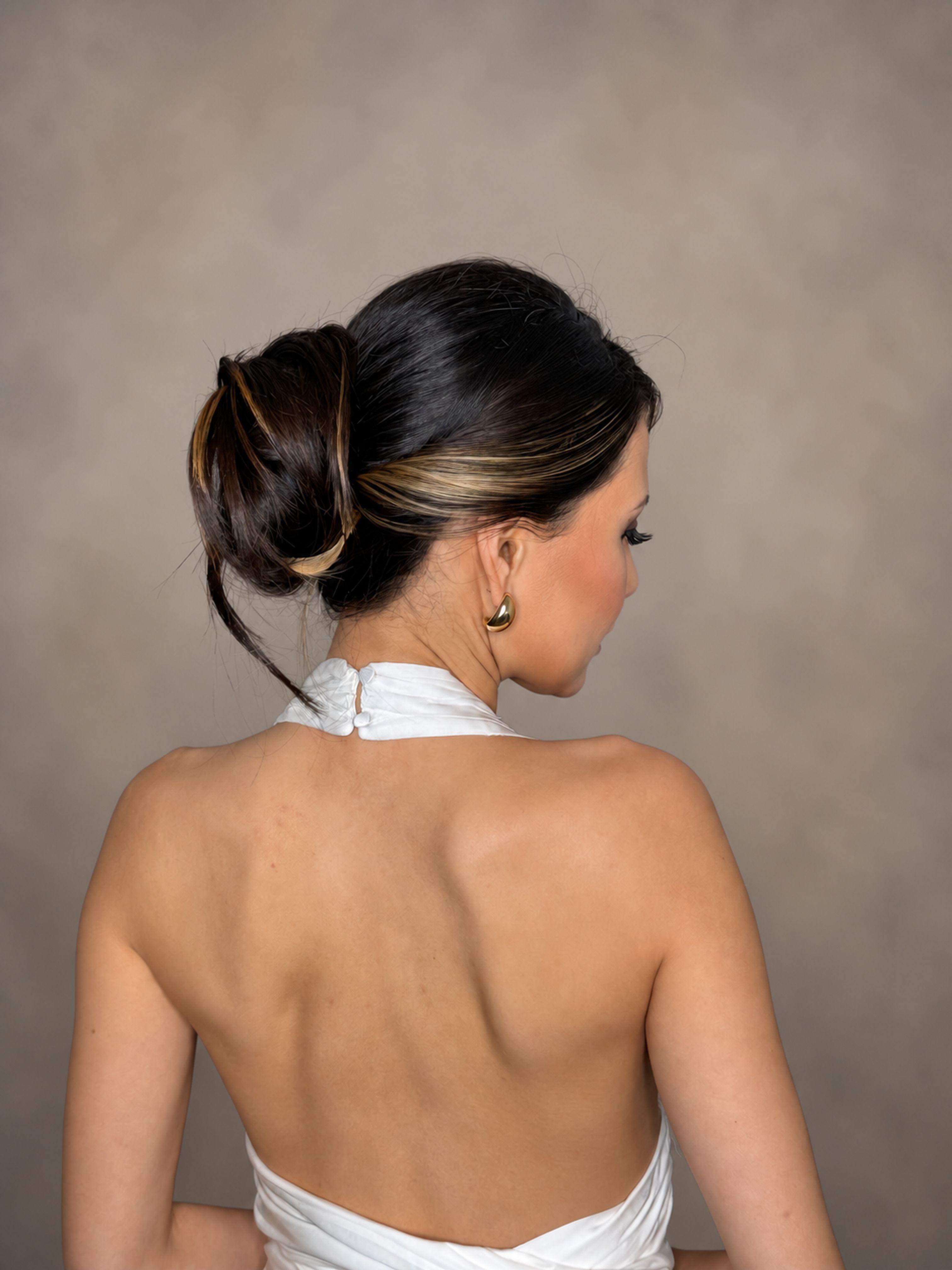 Back view of brunette hair styled in a sleek twisted low bun.