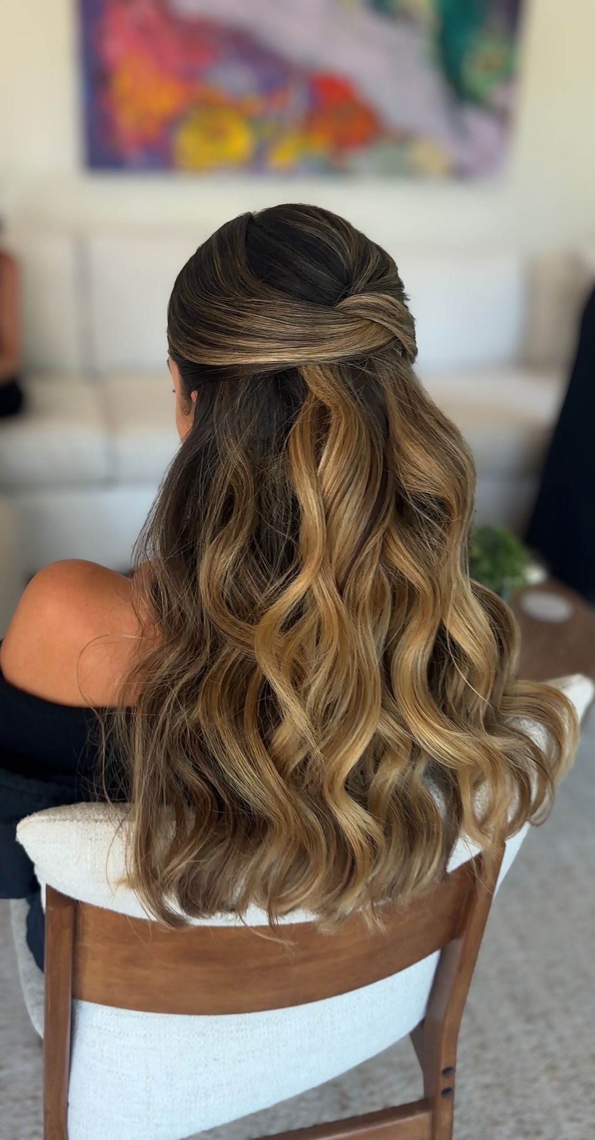 Back view of blonde balayage hair styled in loose waves with a half-up twist.