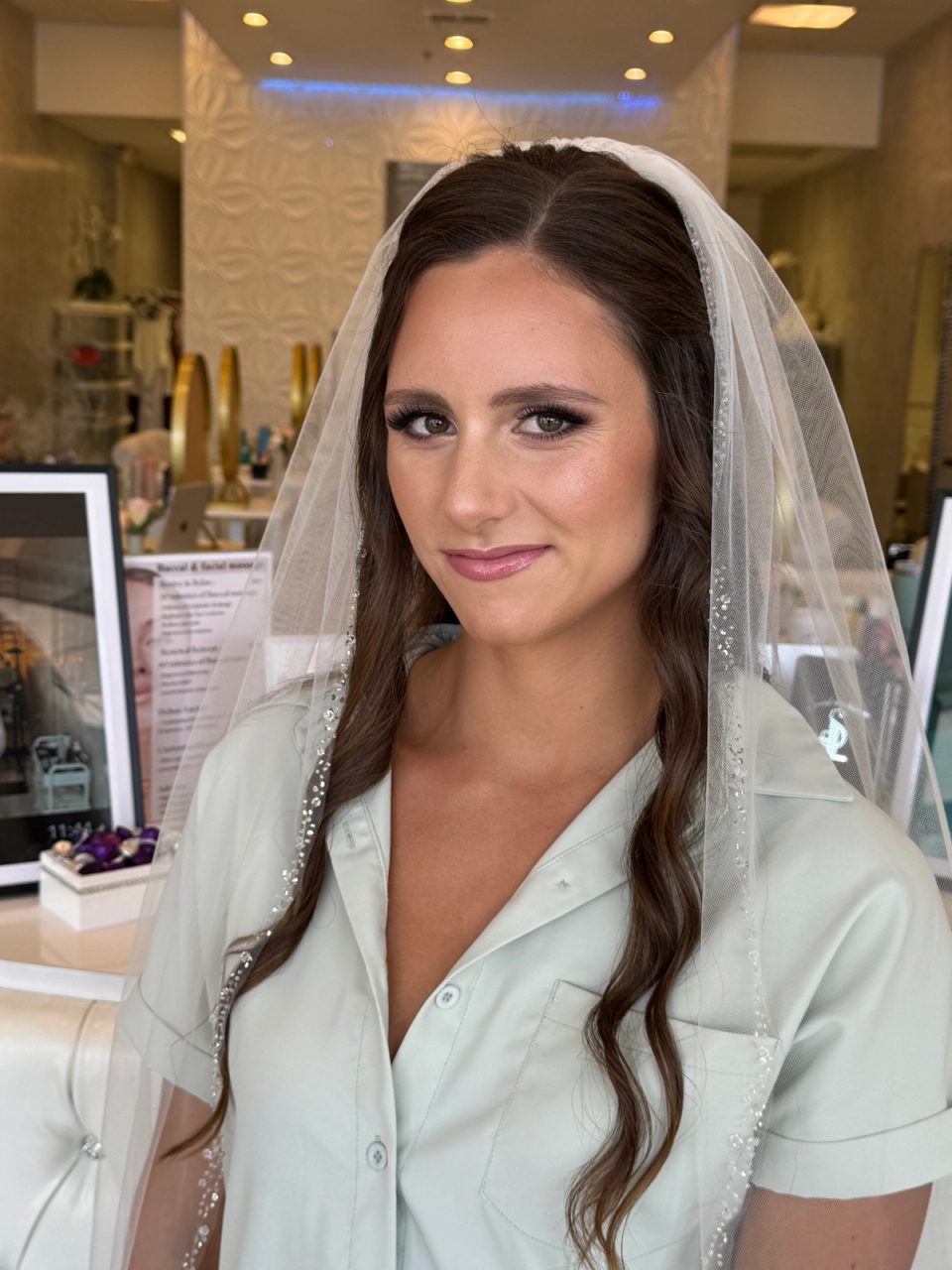 Bride wearing a beaded veil with long brunette hair and softly defined neutral makeup.