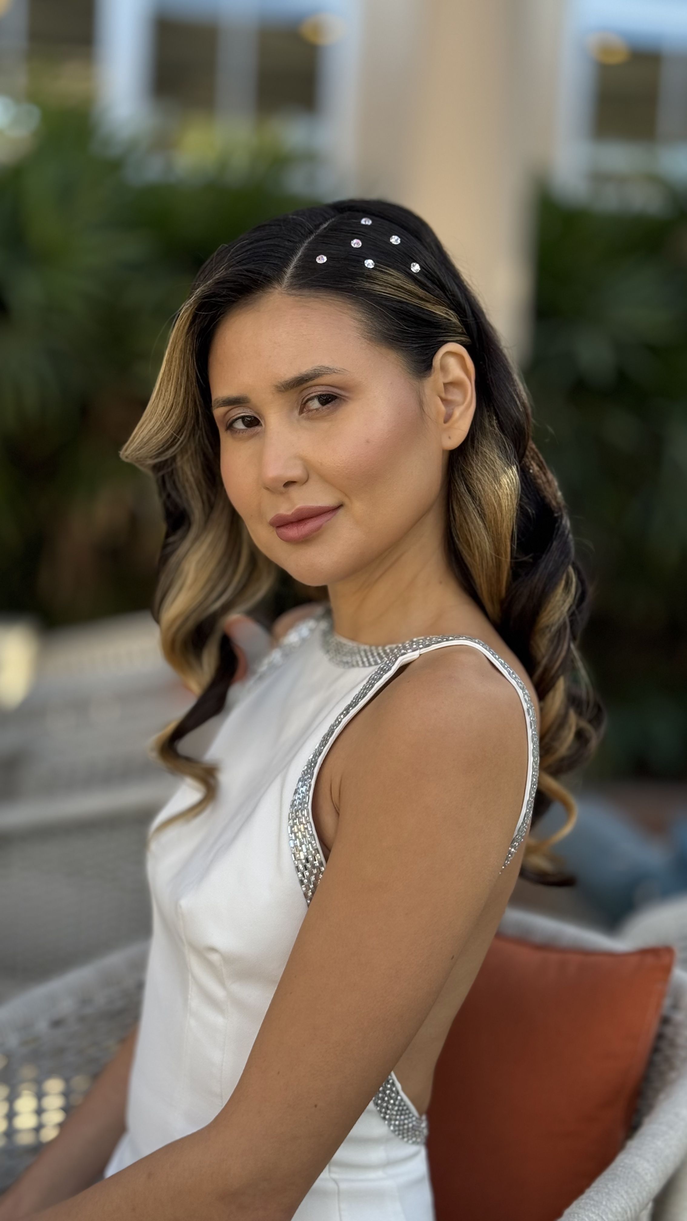 Brunette woman with long soft waves accented by pearl hairpins.
