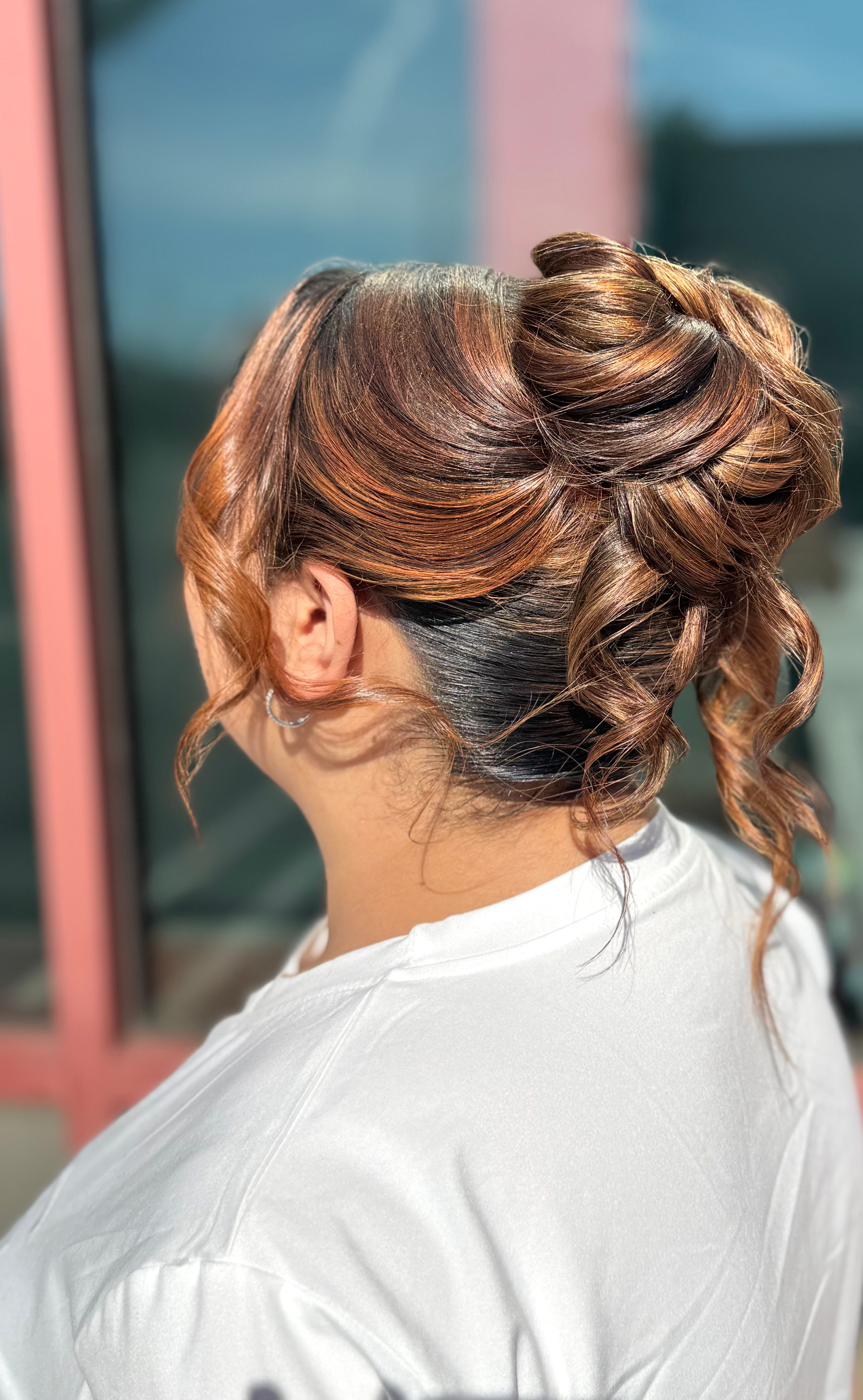Side view of a textured bridal updo with curls and loose tendrils.