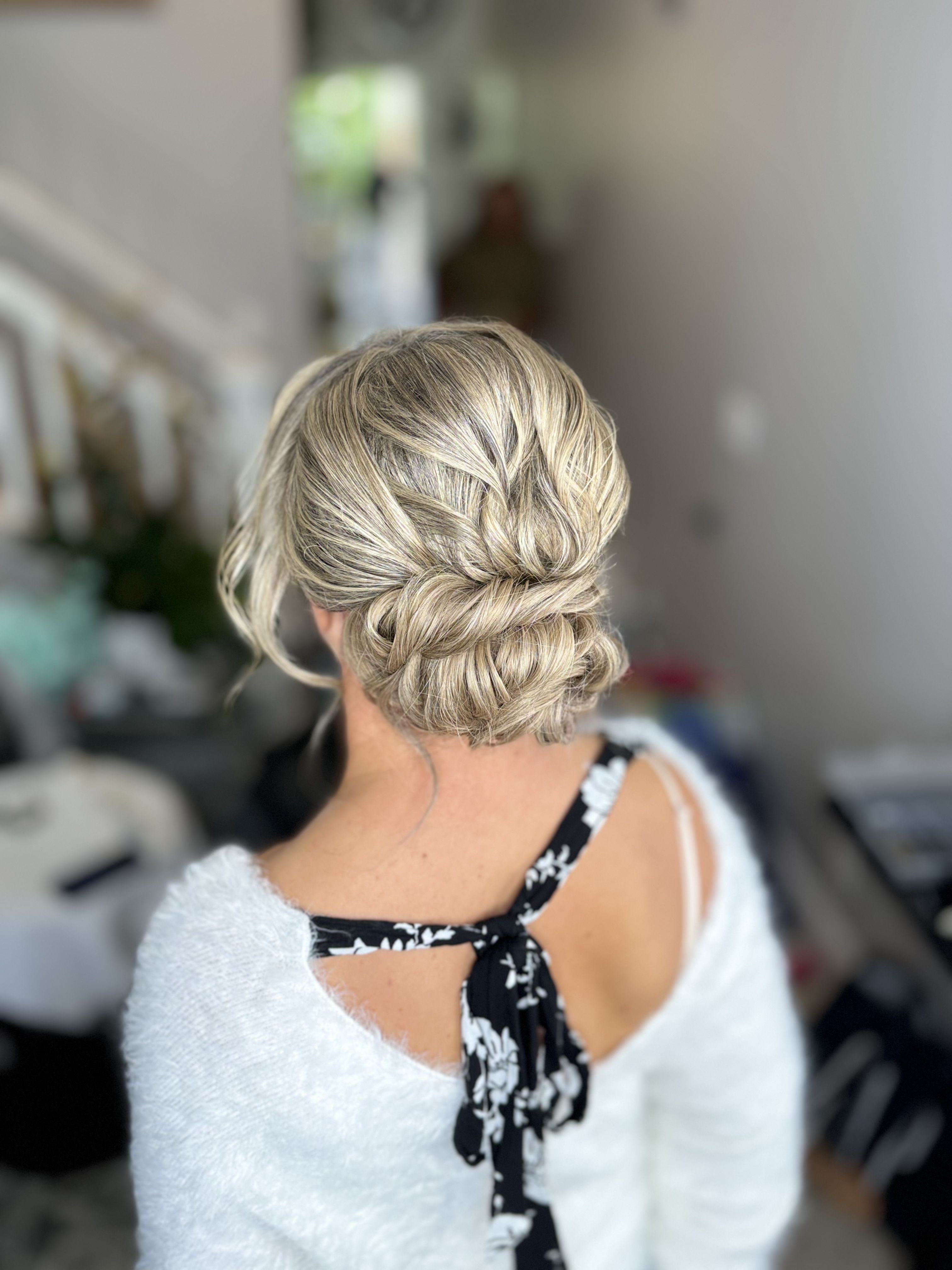 Back view of blonde hair styled in an intricate braided low bun.