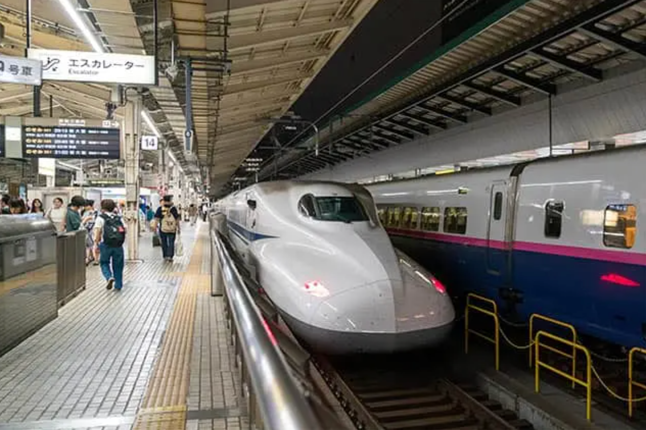 White Shinkansen bullet train at a station platform with people waiting