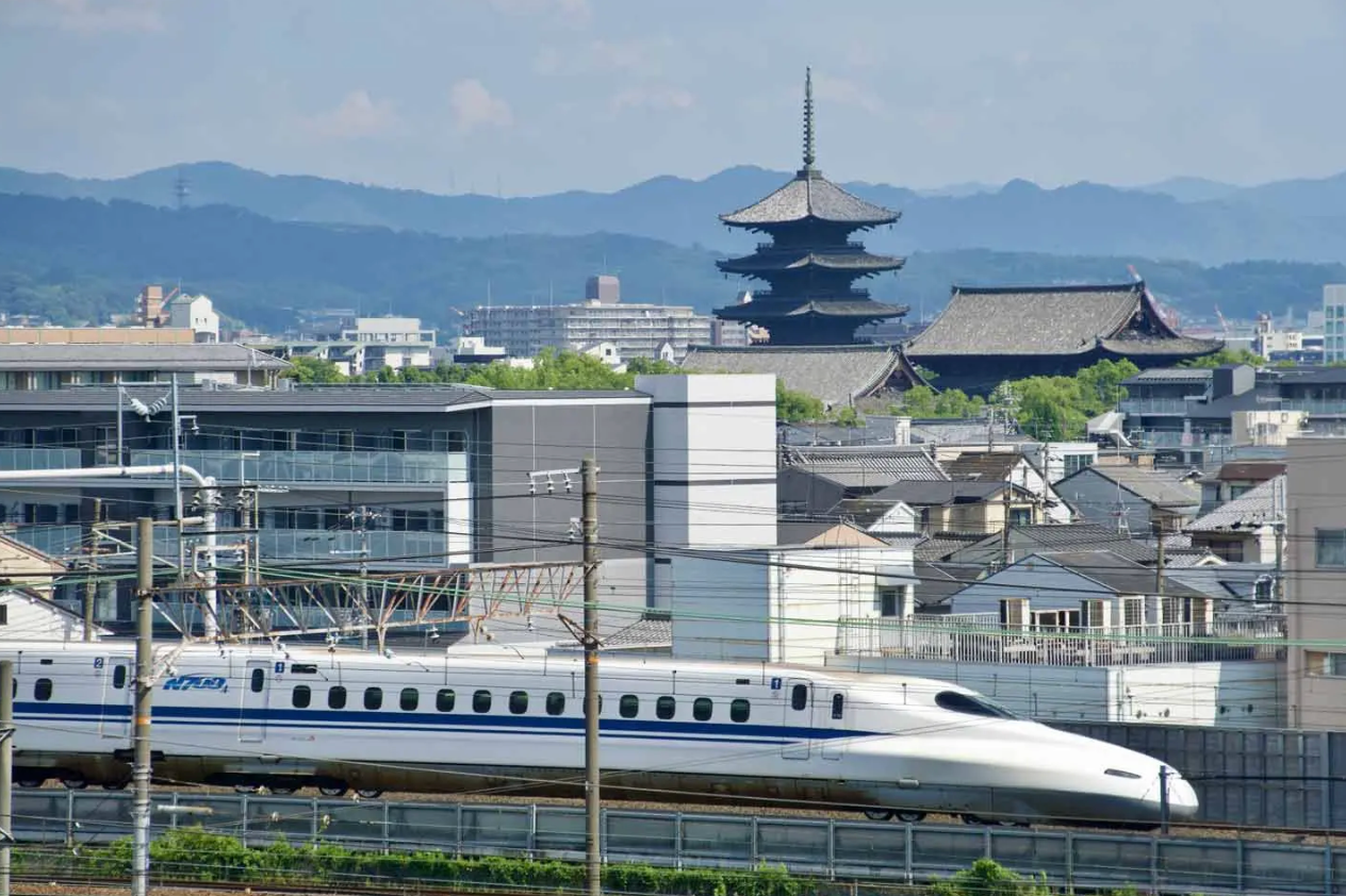 Shinkansen bullet train passing by a five-story pagoda