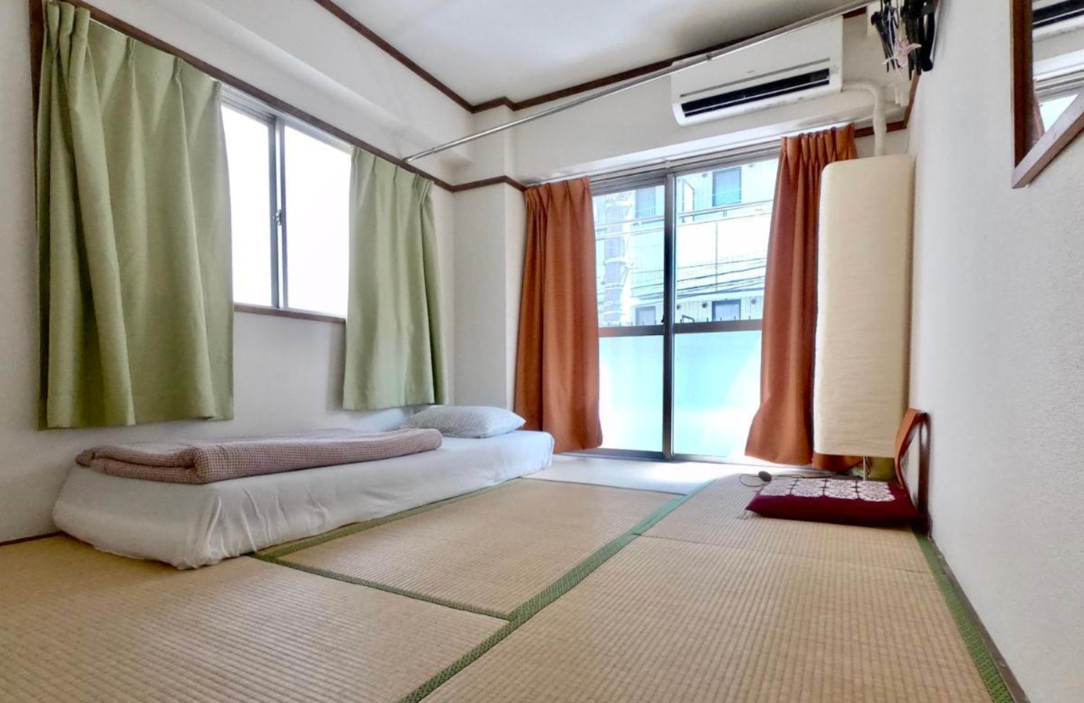 Minimalist Japanese-style room with tatami mats, a futon, and window curtains