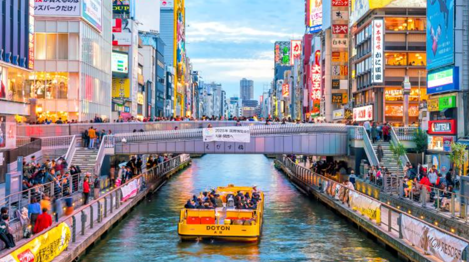 Yellow tour boat on Dotonbori canal with colorful neon signs and Ebisubashi Bridge in Osaka