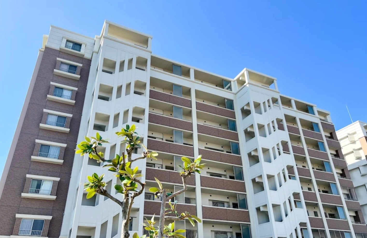 Modern multi-story apartment building with balconies under a clear blue sky