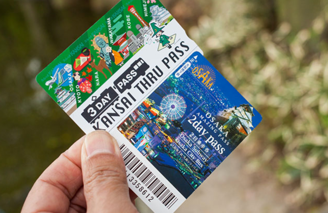 Hand holding a Kansai Thru Pass and an Osaka Amazing Pass for travel in Japan