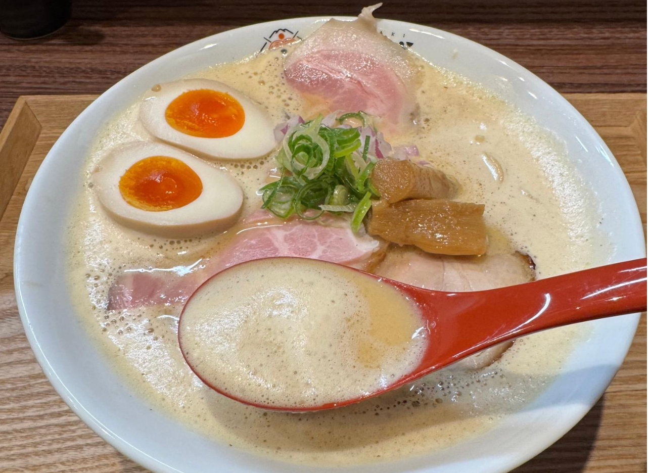 Creamy tori paitan ramen with chashu, soft boiled eggs and a red spoon