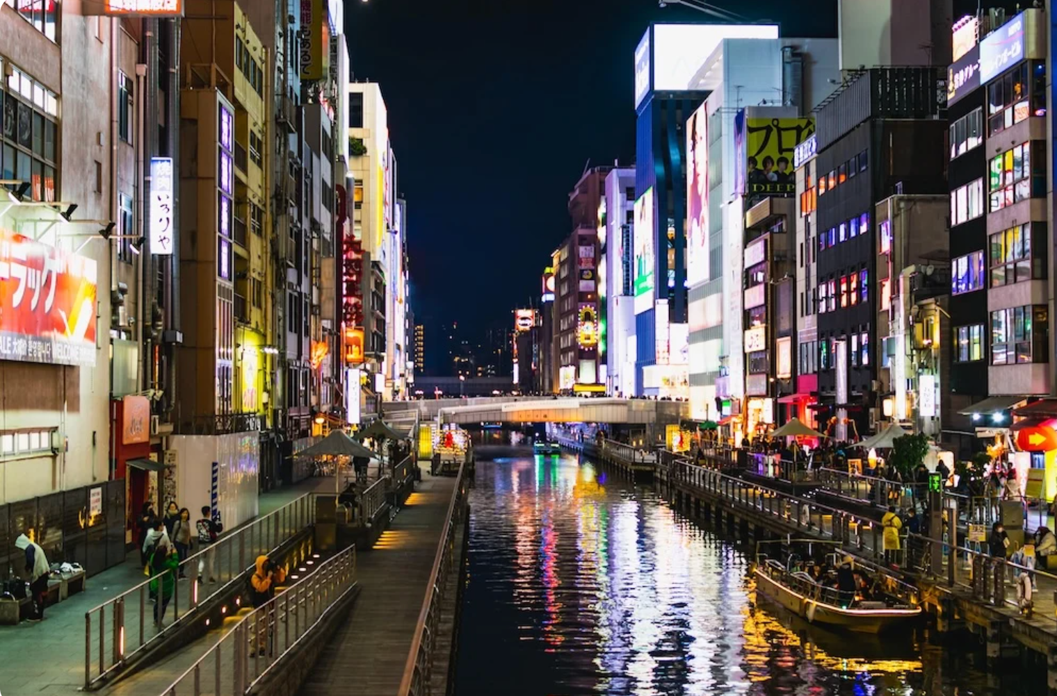 Dotonbori canal at night with bright neon signs and reflections on the water