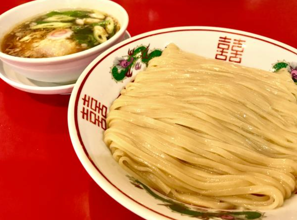 Tsukemen dipping noodles neatly served on a plate next to a bowl of savory soup