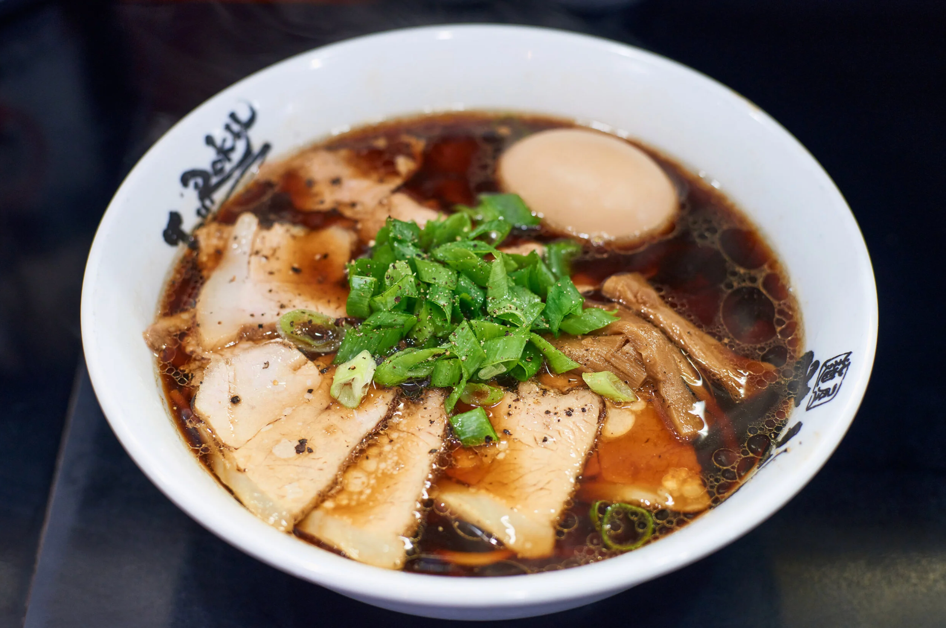 Shoyu ramen topped with chashu pork slices, bamboo shoots, soft-boiled egg, and green onions